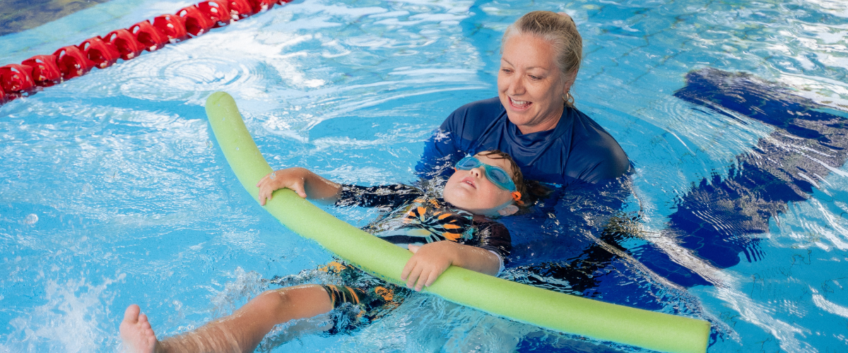 Child swimming underwater with swim teacher or instructor